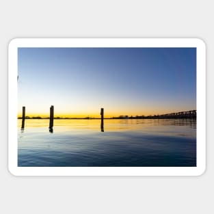 Sweeping lines of Tauranga's historic railway bridge with sunrising on left cast golden hues across harbor Sticker